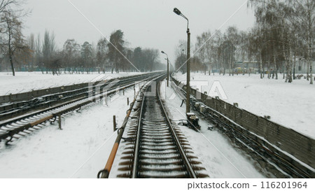 Railway in the winter. High-speed train goes in the winter season. Snow flies in the window of the driver. Long track. 116201964