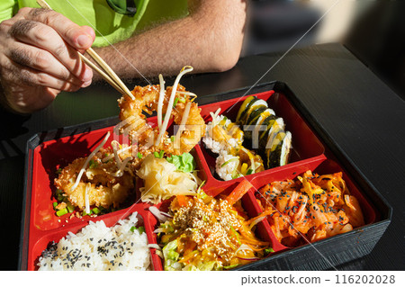 Japanese Lunch in Bento Box with Deep-Fried Squid Rings, Sushi Rolls, Salad, Rice, Pickled Ginger Japanese Lunch in Bento Box with Deep-Fried Squid Rings, Sushi Rolls, Salad, Rice, Pickled Ginger 116202028