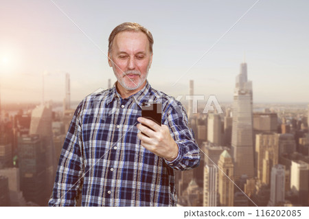 Happy smiling cheerful mature man is using his smartphone. Urban cityscape background. 116202085