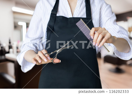 Barber in uniform holding scissors and comb. 116202333