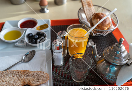 Moroccan breakfast also known as ftour, orange juice, tea, bread, croissant, jam, honey, olives, metal teapot Moroccan breakfast also known as ftour, orange juice, tea, bread, croissant, jam, honey, olives, metal teapot 116202676