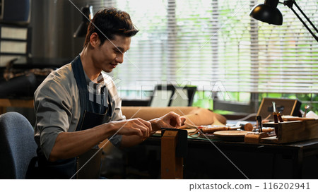 Artisan of leather meticulously stitching leather with a needle and thread. Leather craft concept 116202941