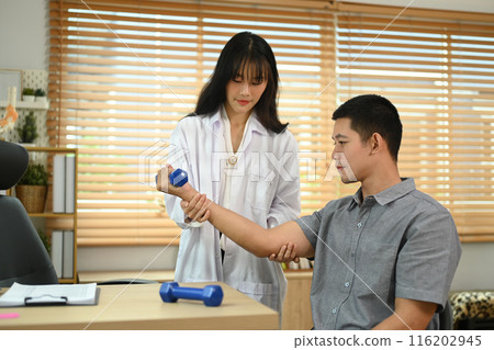 Athlete male patient lifting weights dumbbell under physiotherapist guidance. Rehabilitation and health care concept Athlete male patient lifting weights dumbbell under physiotherapist guidance. Rehabilitation and health care concept 116202945