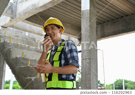 Engineer man wearing safety uniform using walkie talkie in work at construction site 116202963