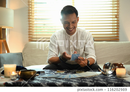 Fortune teller spreading tarot cards on desk with various spiritual items. Forecasting and divination concept Fortune teller spreading tarot cards on desk with various spiritual items. Forecasting and divination concept 116202989