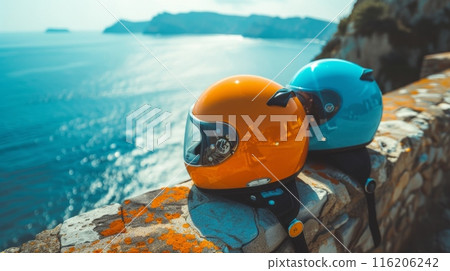 Two motorcycle helmets resting on wall with sea on background sunny day time with blue sky. Summer motorbike vacation. 116206242