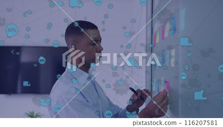 Image of network of icons over african american man sticking memo notes on board at office 116207581