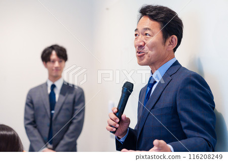 Middle-aged man giving a speech using a microphone Middle-aged man giving a speech using a microphone 116208249