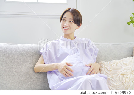 Smiling pregnant woman in the living room Smiling pregnant woman in the living room 116209950