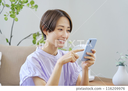A woman using a smartphone in the living room 116209976