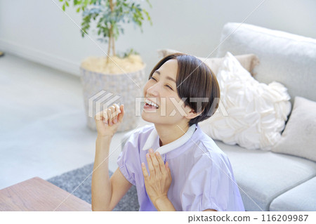 Woman using ice neck ring in living room 116209987