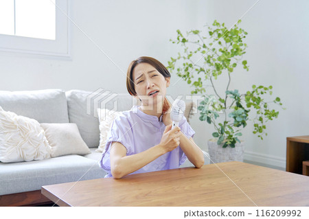 一位女士在潮濕的客廳使用便攜式風扇 116209992
