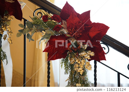 A red Christmas wreath on the staircase railing 116213124