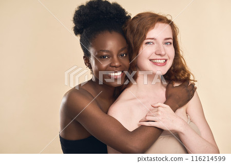 Diverse Women Smiling and Embracing Each Other in Studio Setting 116214599