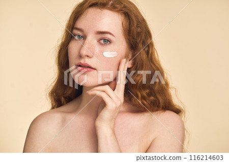 Young Woman Applying Skincare Cream on Face in Beauty Shot Young Woman Applying Skincare Cream on Face in Beauty Shot 116214603