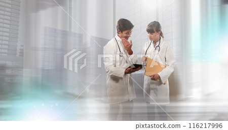 Image of a young caucasian female medical professional holding folder is discussing with a colleague 116217996
