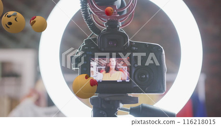 Image of emoji icons over female vlogger on camera viewer recording vlog at home 116218015