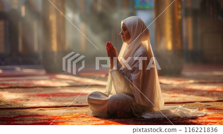 Young muslim woman praying in mosque wearing traditional clothes Young muslim woman praying in mosque wearing traditional clothes 116221836
