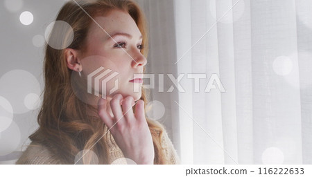 Image of light spots over caucasian woman looking through window Image of light spots over caucasian woman looking through window 116222633