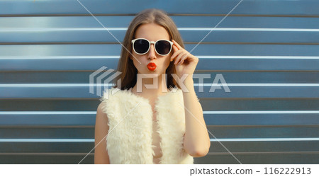 Modern stylish young woman blowing kiss in white glasses, fashionable girl posing on gray background Modern stylish young woman blowing kiss in white glasses, fashionable girl posing on gray background 116222913
