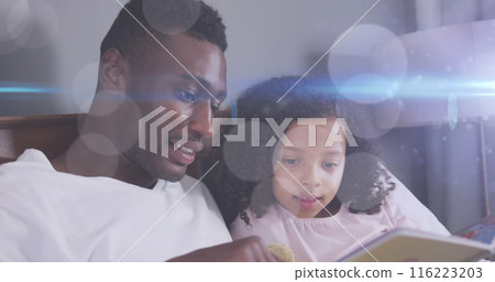 Image of light spots over happy african american father reading book with daughter Image of light spots over happy african american father reading book with daughter 116223203