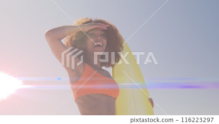 Image of lights over african american woman holding surfboard Image of lights over african american woman holding surfboard 116223297
