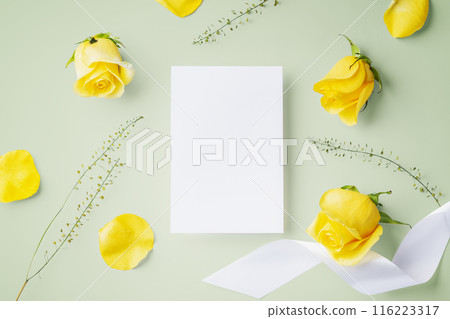 White card with yellow rose and ribbon on light green background, top view White card with yellow rose and ribbon on light green background, top view 116223317
