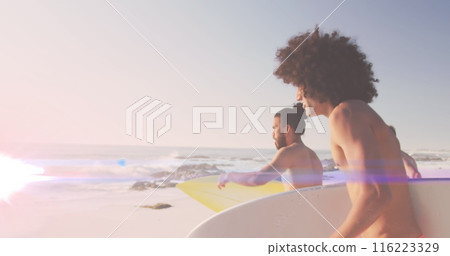Image of light over happy diverse male friends running on beach with surfboards 116223329
