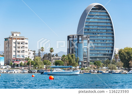 Modern oval shaped skyscraper towering over the Limassol skyline on a sunny summer day. Cyprus Modern oval shaped skyscraper towering over the Limassol skyline on a sunny summer day. Cyprus 116223593