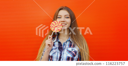 Portrait happy cheerful smiling teenager girl holding colorful lollipop on red background Portrait happy cheerful smiling teenager girl holding colorful lollipop on red background 116223757