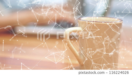 Person typing on laptop with coffee mug in foreground, digital network overlay visible Person typing on laptop with coffee mug in foreground, digital network overlay visible 116224026
