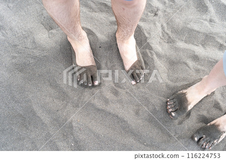 Bare foot on black sand, black volcanic beach barefoot person, dirty family feet on dark sea sand 116224753