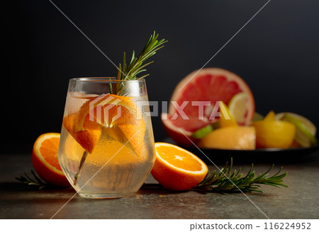 Cocktail gin tonic with ice, rosemary, and orange on a stone table. 116224952