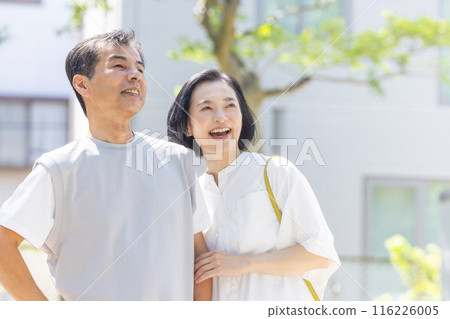 Senior couple cuddling in front of an apartment 116226005