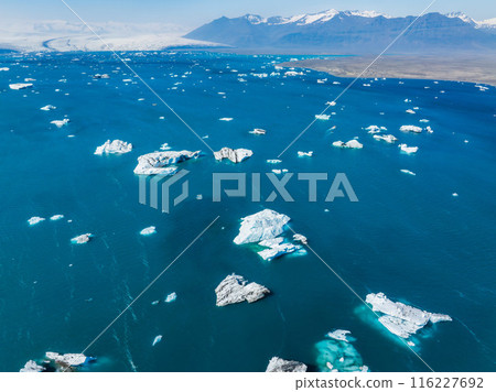 Aerial view of the big pieces of ice from glacier, ice islands, glacier and mountains, Jokulssrlon - Glacier Lagoon. A large glacial lake in southern part of Vatnajokull National Park, Iceland Aerial view of the big pieces of ice from glacier, ice islands, glacier and mountains, Jokulssrlon - Glacier Lagoon. A large glacial lake in southern part of Vatnajokull National Park, Iceland 116227692