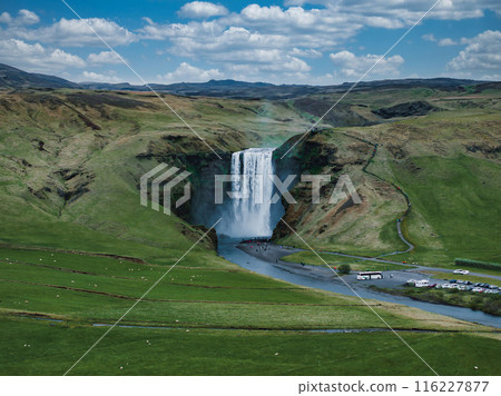 Impressively beautiful nature of Iceland during sunset. Skogafoss waterfall is one famous natural landmark and travel destination place of Iceland. Tourists ride horses near famouse waterfall. 116227877
