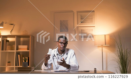 Pharmaceutical consulting. Doctor appointment. Professional telehealth. Confident male physician introducing medication pills at modern workplace interior with free space. Pharmaceutical consulting. Doctor appointment. Professional telehealth. Confident male physician introducing medication pills at modern workplace interior with free space. 116227929