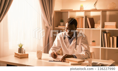 Doctor lifestyle. Medic career. Professional occupation. Confident busy male physician in white coat working writing prescription at light modern interior with free space. Doctor lifestyle. Medic career. Professional occupation. Confident busy male physician in white coat working writing prescription at light modern interior with free space. 116227990