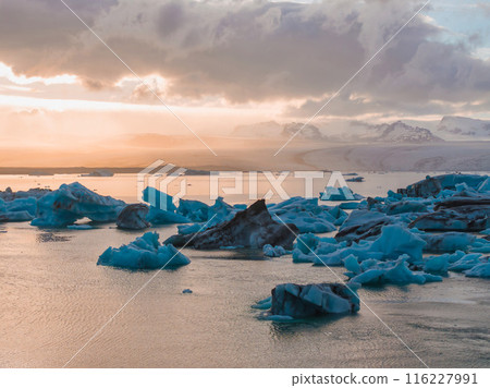 Beautiful sunset with melting icebergs of emerald turquoise blue in Jokulsarlon glacier lagoon in Iceland. 116227991