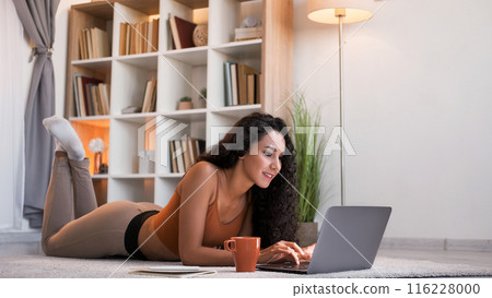 Freelance work. Home online. Internet research. Relaxed cheerful girl typing on laptop at modern home living room interior with copy space. Freelance work. Home online. Internet research. Relaxed cheerful girl typing on laptop at modern home living room interior with copy space. 116228000