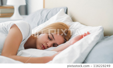 Bed rest. Morning nap. Lazy day. Young peaceful girl enjoying sleeping dreaming relaxing on soft pillow in comfortable bright room. 116228249