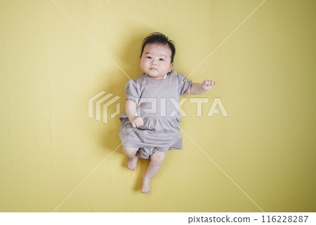 Baby girl lying on a yellow background 116228287