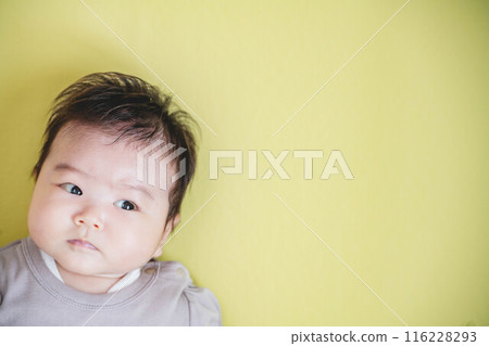 Baby girl lying on a yellow background 116228293