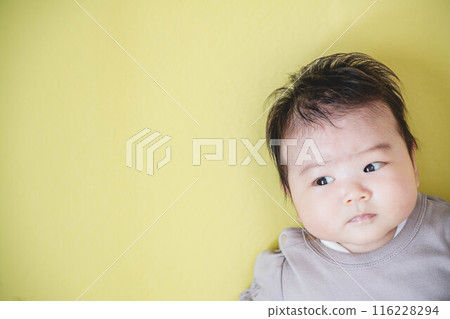 Baby girl lying on a yellow background 116228294