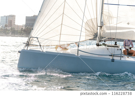 Competitive sailing boat gliding on sunny day 116228738