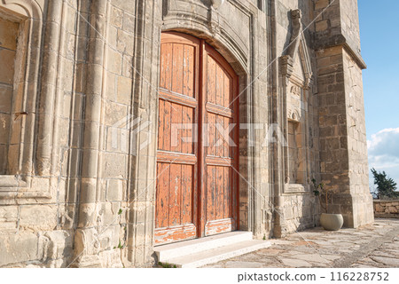 Old wooden door on a weathered stone Church of Timios Prodromos facade at Vouni village. Limassol District, Cyprus Old wooden door on a weathered stone Church of Timios Prodromos facade at Vouni village. Limassol District, Cyprus 116228752