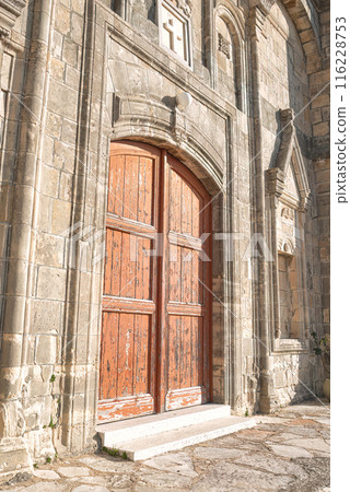 Old wooden door on a weathered stone Church of Timios Prodromos facade at Vouni village. Limassol District, Cyprus 116228753