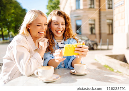 Two young women sitting in the cafe. Coffee break after shopping. Blogging, tourism. 116228791