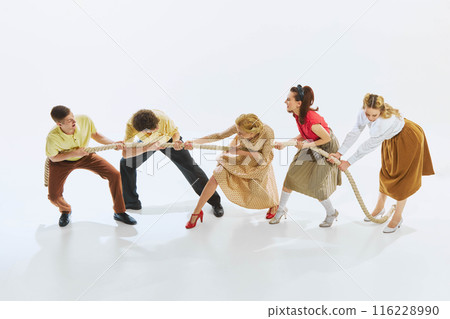 Group of men and women in vintage clothing engage in lively game of tug-of-war. People pulling rope, symbolizing competition and ambitions 116228990