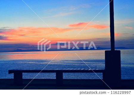 A bench overlooking the sunset and the sea A bench overlooking the sunset and the sea 116228997